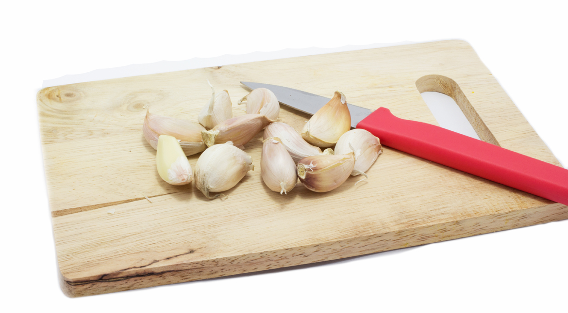 Chopping the garlic with knife on white